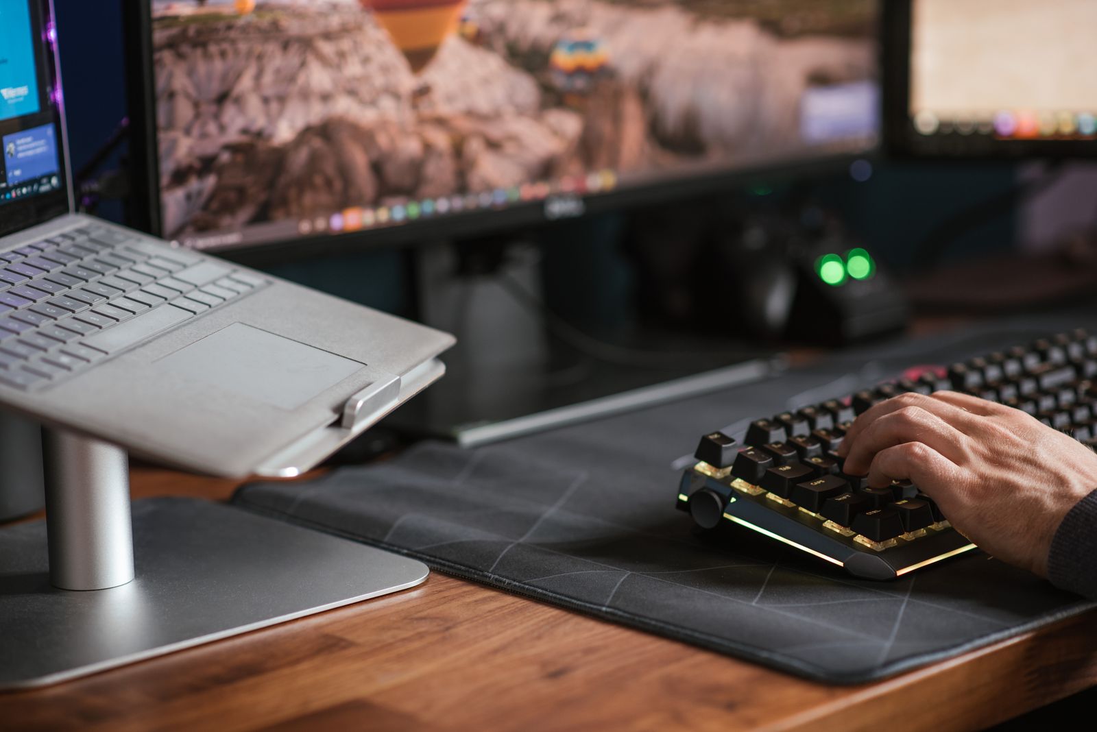 ノートパソコンと外部モニターを並べたデスクでキーボードを操作している様子